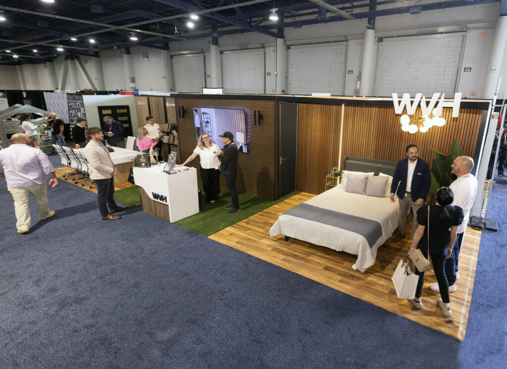 wide angle shot of wood veneer hub's trade show booth design featuring a mock bedroom with wood paneling along the wall