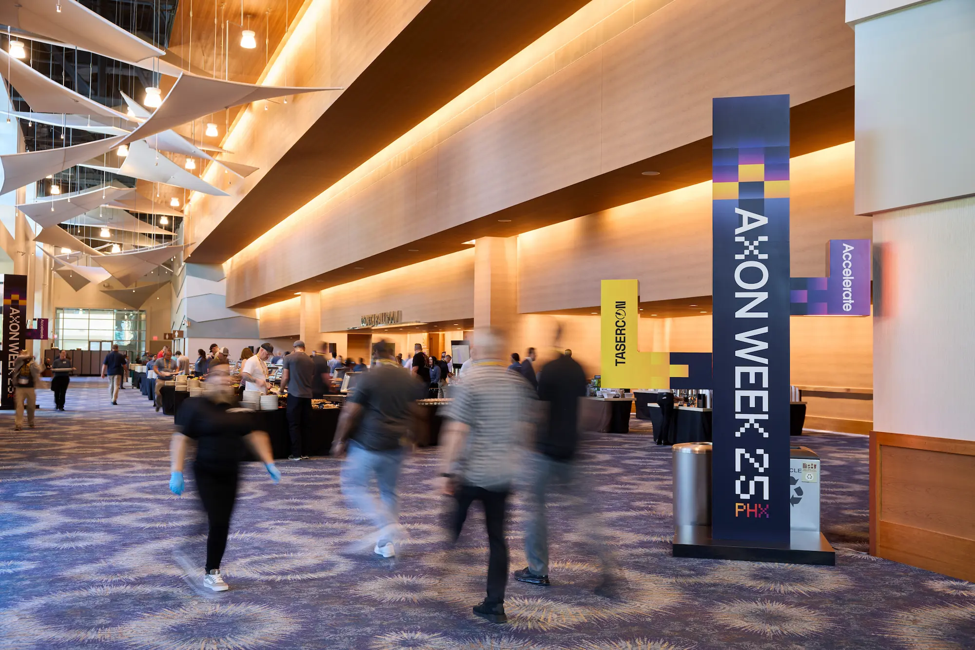 Axon Week 2025 corporate event hallway with branded totem signage and attendees moving between sessions produced by Highway 85 Productions