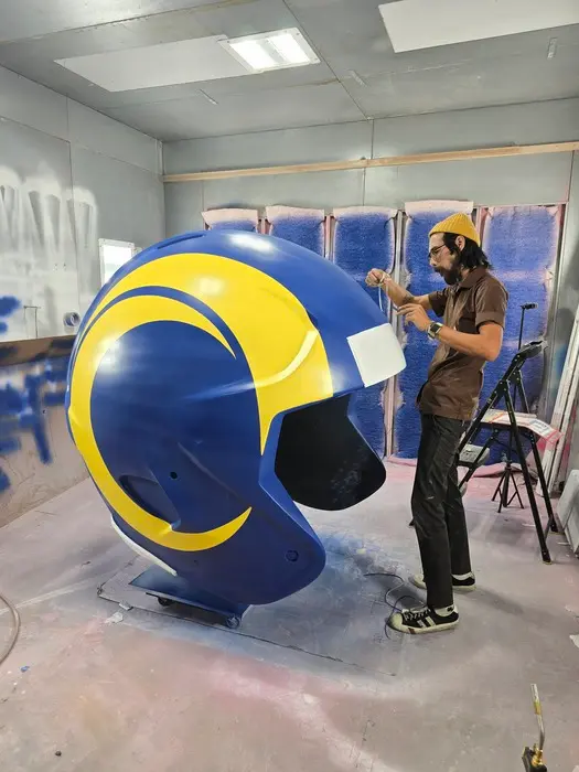 Highway 85 Productions fabricator finishing a large scale custom LA Rams helmet prop in the paint booth as part of an agency client activation project
