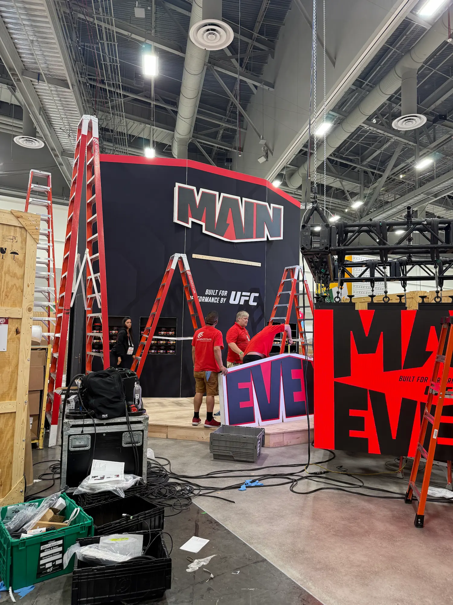 Main Event UFC custom trade show booth engineering and installation in progress with rigging crew assembling large format structure on the show floor by Highway 85 Productions