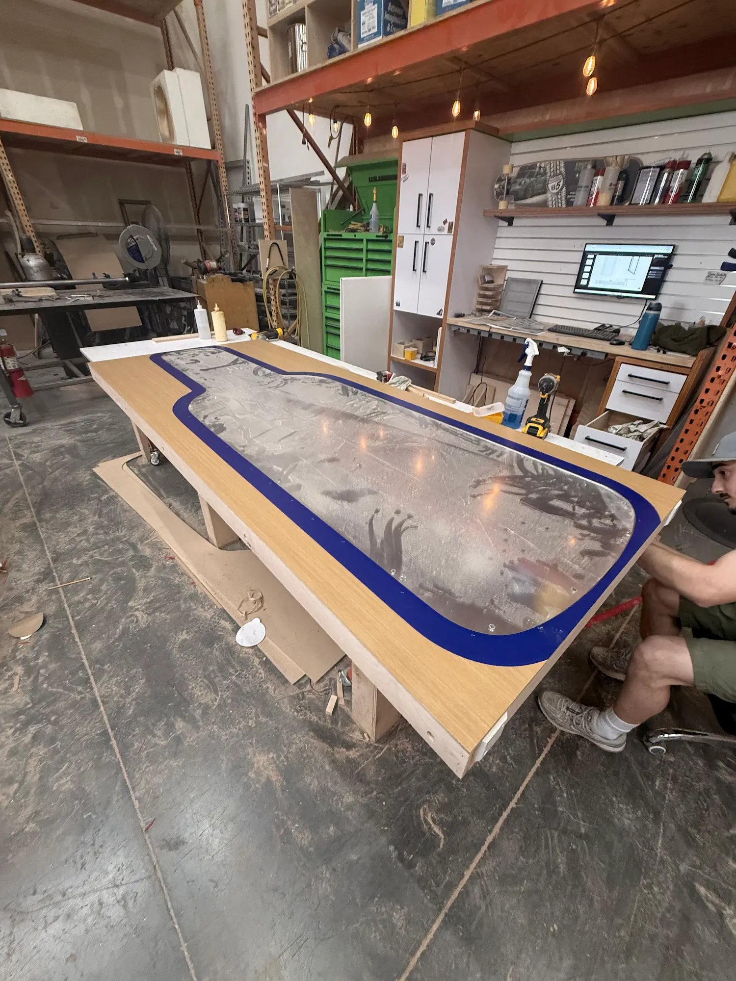 Highway 85 Productions fabrication team applying custom acrylic and laminate trade show booth materials to a branded counter surface in the shop